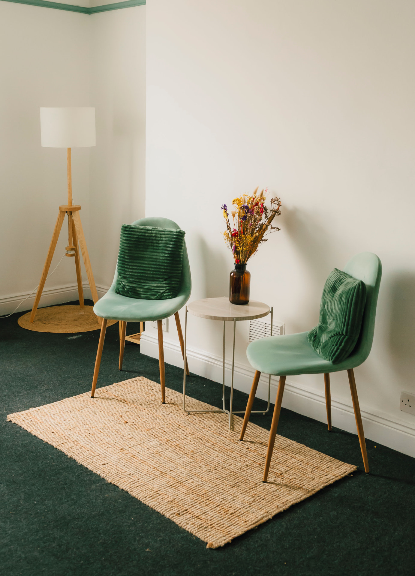 Two sage green chairs and a side table with dried flowers in the Aphrodite Room