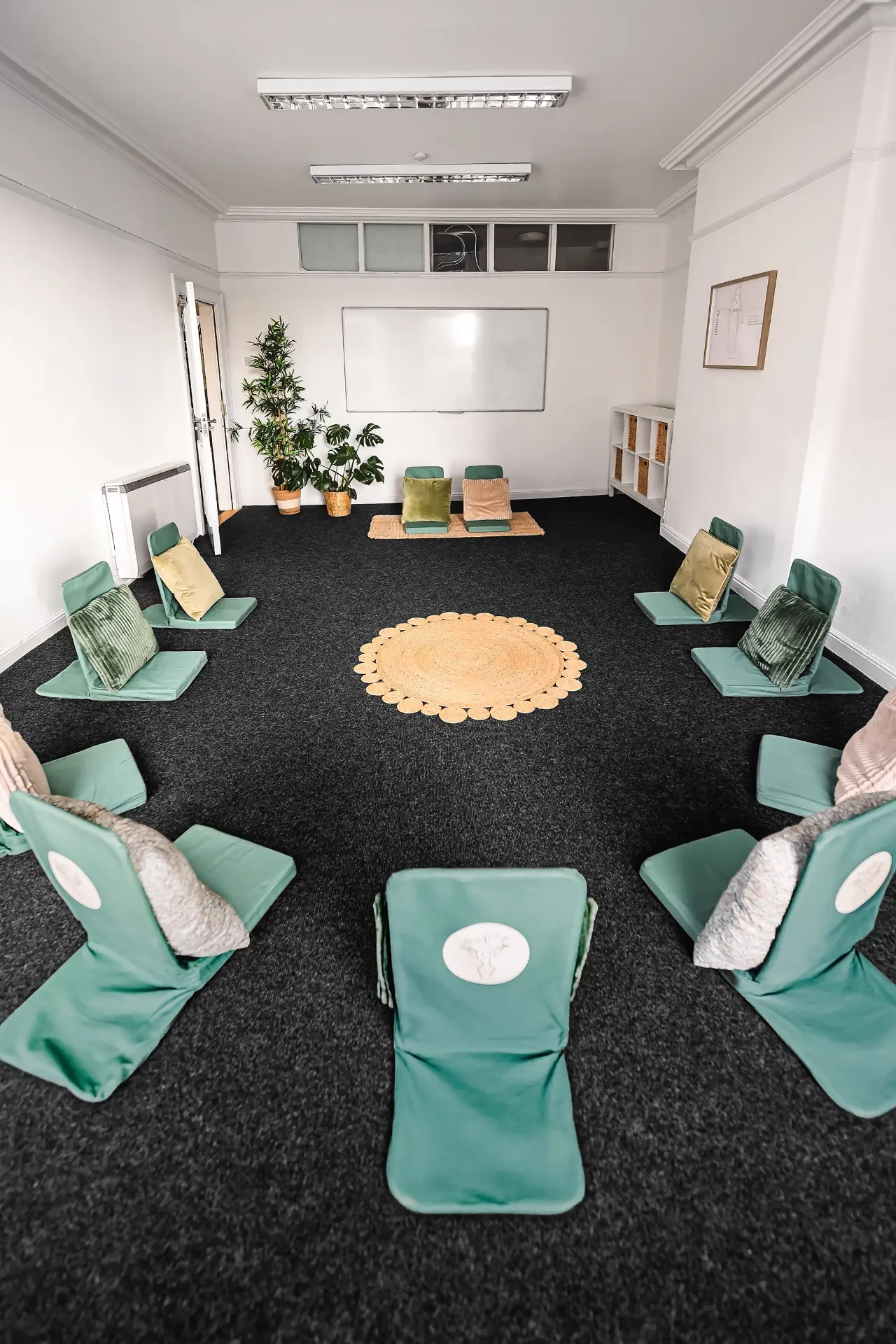 Brigid Room with sage green floor chairs arranged in a circle around a woven mat