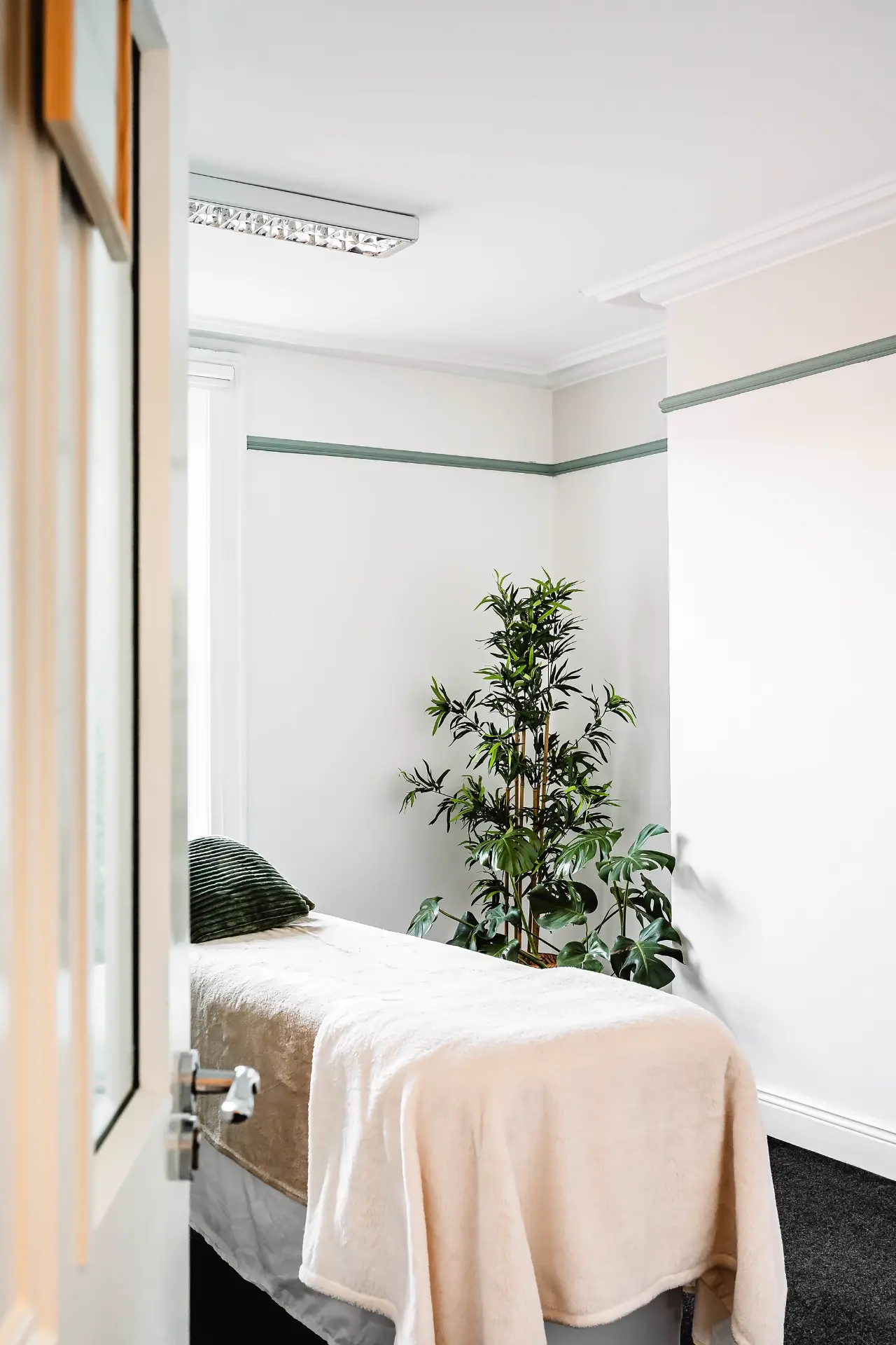 Treatment couch with soft blankets beside plants in the Aphrodite Room
